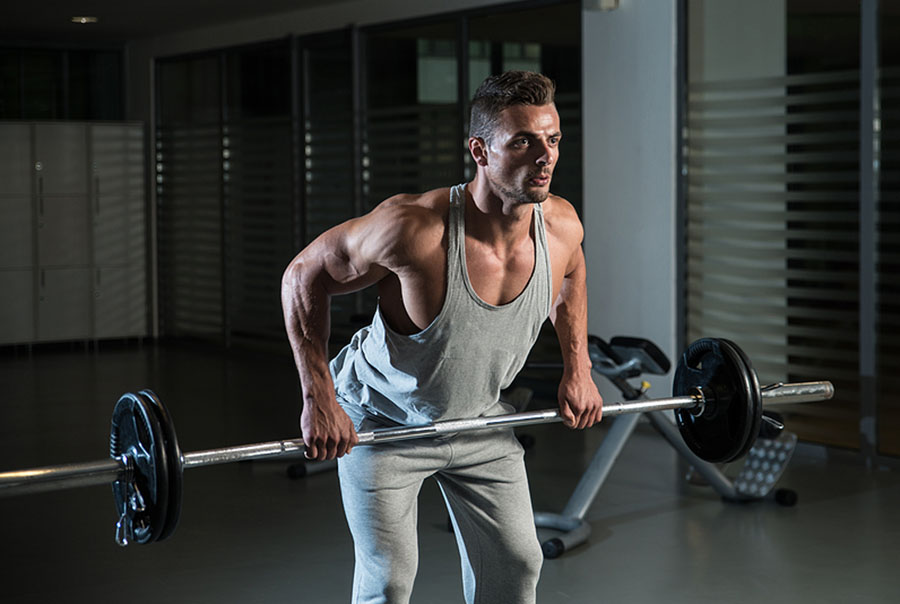 Muscular man doing barbell row, tracking how many sets