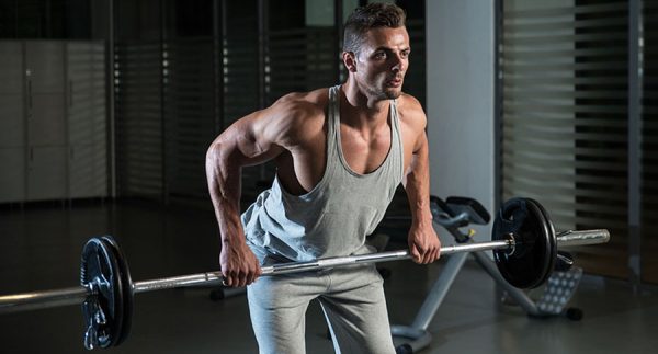 Muscular man doing barbell curls preparing to superset with chest