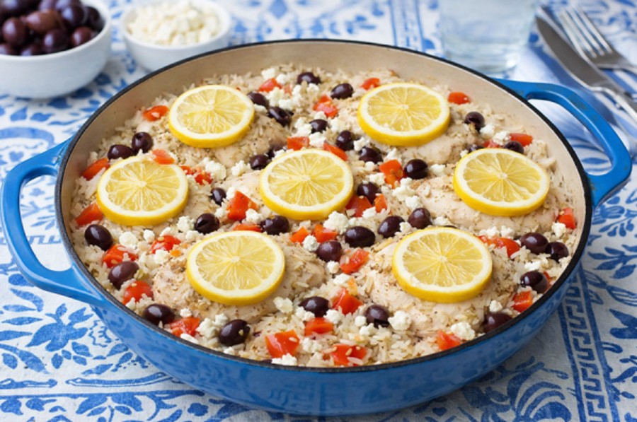 eine blaue Pfanne mit Griechischen Hähnchenoberschenkel mit Reis, Zitronenscheiben, Oliven und Feta