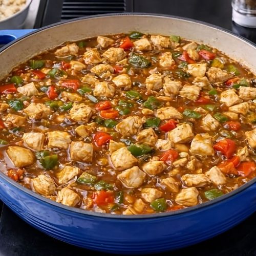 Honig-Senf-Hähnchen mit Paprika und Zwiebeln in einer emaillierten Pfanne, servierfertig und proteinreich