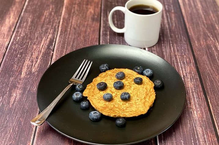 Süßkartoffel-Protein-Pfannkuchen auf einem Teller mit Blaubeeren