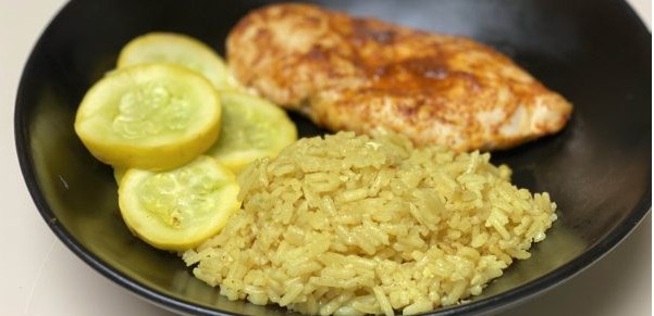Ein Teller mit Kokos-Curry-Reis, Gemüse und Hähnchen