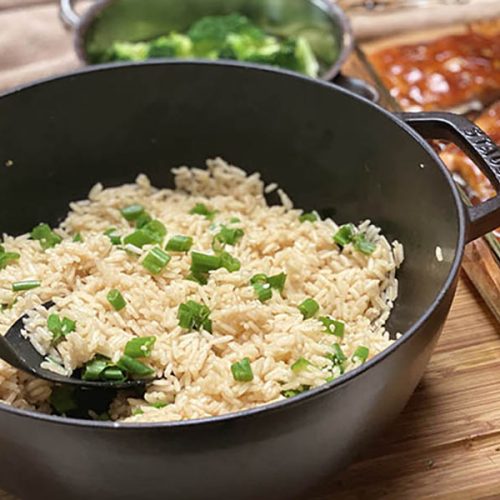 Ein Kochtopf gefüllt mit Reis mit Sesam, daneben etwas Hühnchen und Brokkoli