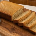 Bananenbrot auf einem Holzbrett mit vier Scheiben