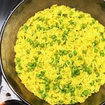 Eine Pfanne mit Kurkuma-Reis und Erbsen auf dem Herd