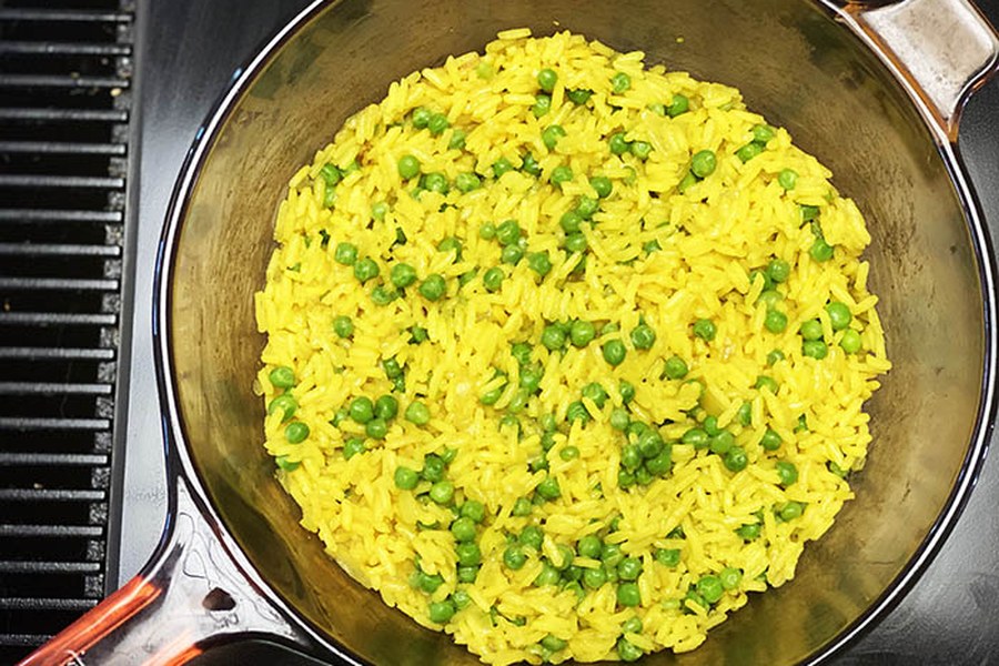 Eine Pfanne mit Kurkuma-Reis und Erbsen auf dem Herd