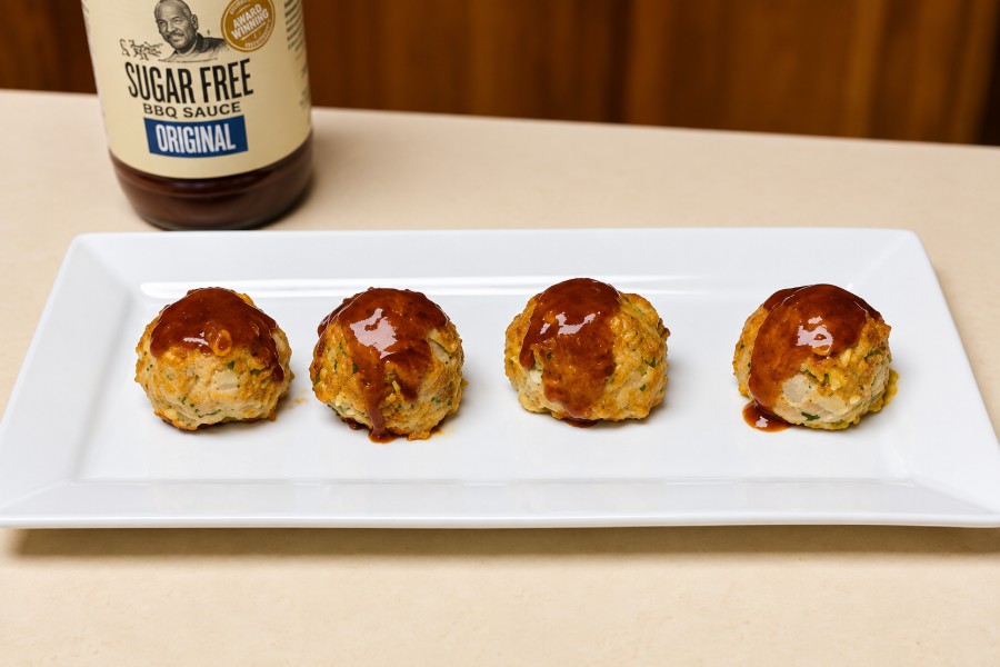 Vier Putenhackbällchen aus dem Ofen mit BBQ-Sauce auf einer weißen Platte.